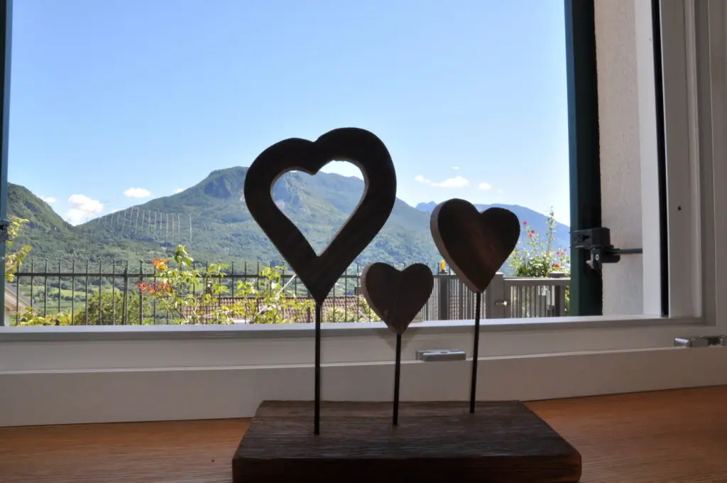 Cuori in legno con le montagne sullo sfondo, alloggio Il Fiore del Calisio a Villamontagna, Trento